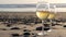 Two wineglasses on ocean beach. Glasses with white wine for romantic date, sea water. Sunset waves.