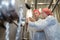 two winery workers in uniform looking at wine vat