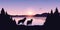 Two wolves look to the lake and mountain landscape at sunrise