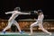 Two woman fencing athletes fight