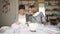 Two woman friends study knitting yarn wool sitting on table in home room