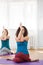 Two woman showing asana is gomukhasana with eagle arms indoor