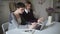 Two woman students sitting at table and using notebook for online learning