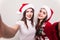 Two woman take selfie from hands in santa hat.