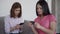 Two woman talking, holding smartphone and card in hand, sitting at sofa in apartment.