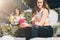 Two women athletes in sports clothes are sitting on bench, relax after sports training, use smartphones, listen to music