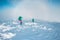 Two women with backpacks walk in snowshoes in the snow