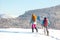 Two women with backpacks walk in snowshoes in the snow