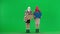 Two women in balaclavas and faux fur coats picketing in the studio on the green screen. Women point to posters and