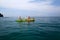 Two women in bikini or swimwear are enjoying canoe or kayak on Andaman Sea with speedboat, island and clear blue sky background