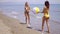 Two women in bikinis playing with a beach ball