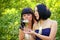 Two women blowing on dandelion in the park