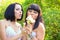 Two women blowing on dandelion in the summer park