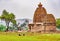 Two women care for grass in front of a Bhuthnath temple carved with intricate Hindi gods