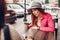 Two women chatting while having coffe in outdoor cafe. Happy friends using phone checking pictures. Girls hang out