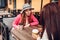 Two women chatting while having coffe in outdoor cafe. Happy friends using phone checking pictures. Girls hang out and having fun