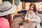 Two women chatting while having coffe in outdoor cafe. Happy friends using phone. Girls hang out