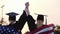 Two women college graduates raise their hands up, on the shoulders of the USA flag