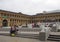 Two women in conversation sat on the steps of the piece hall in halifax west yorkshire with people shopping and sat in cafes and