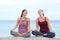 Two women doing yoga laughing on the beach