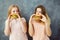 Two women eating burgers and look at each other