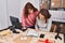 Two women ecommerce business workers writing on document at office