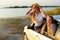 Two women enjoying road trip on a summer day at seaside. Excited young female friends leaning out of car windows and