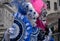 Two women with fans, wearing hand painted masks and ornate blue and pink costumes at Venice Carnival