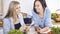 Two women friends choosing the recipe for a delicious meal while sitting at the table in the kitchen. Tablet pc is the