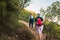 two women friends climbing to the top of a mountain. young people on holiday. women hiking on a woods trail.