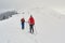 Two women friends hiking and ski touring side by side on a ridge, with overcast sky, above Azuga ski resort, Prahova Valley.