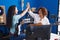 Two women guitarist high five with hands raised up at music studio