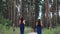 Two women harpists walk away along a forest road and play harps.
