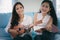 Two women are having fun playing ukulele and smiling at home for