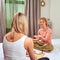 Two women hold a Chinese tea ceremony on a home bed in the bedroom, a tray with a teapot, cups and candles