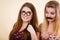 Two women holding moustache and eyeglasses on stick