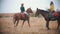 Two women in jackets riding horses on the autumn field