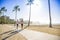 Two Women jogging on the beach boardwalk between two palm trees