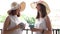 Two women in large summer hats on the balcony talking