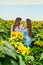 Two women lean on each other on sunflower field