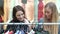 Two Women Looking At Clothes On Rail In Shopping Mall