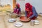 Two women making chapati bread outside their home