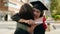 Two women mother and graduated daughter holding diploma kissing at street