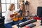 Two women musicians singing song playing classical guitar and ukulele at music studio