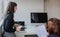 Two women in office outfit working on computers and discussing a report