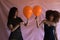 Two women, one blonde and the other Afro-American, young and beautiful, playing with orange balloons at a Halloween party. Concept