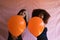 Two women, one blonde and the other Afro-American, young and beautiful, playing with orange balloons at a Halloween party. Concept