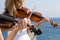 Two women play violin on beach