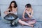 Two women playing handpan and melodica blow organs sitting on the floor.
