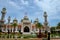 Two women pose at Pattani central mosque courtyard with pond minarets and Thai flag Thailand